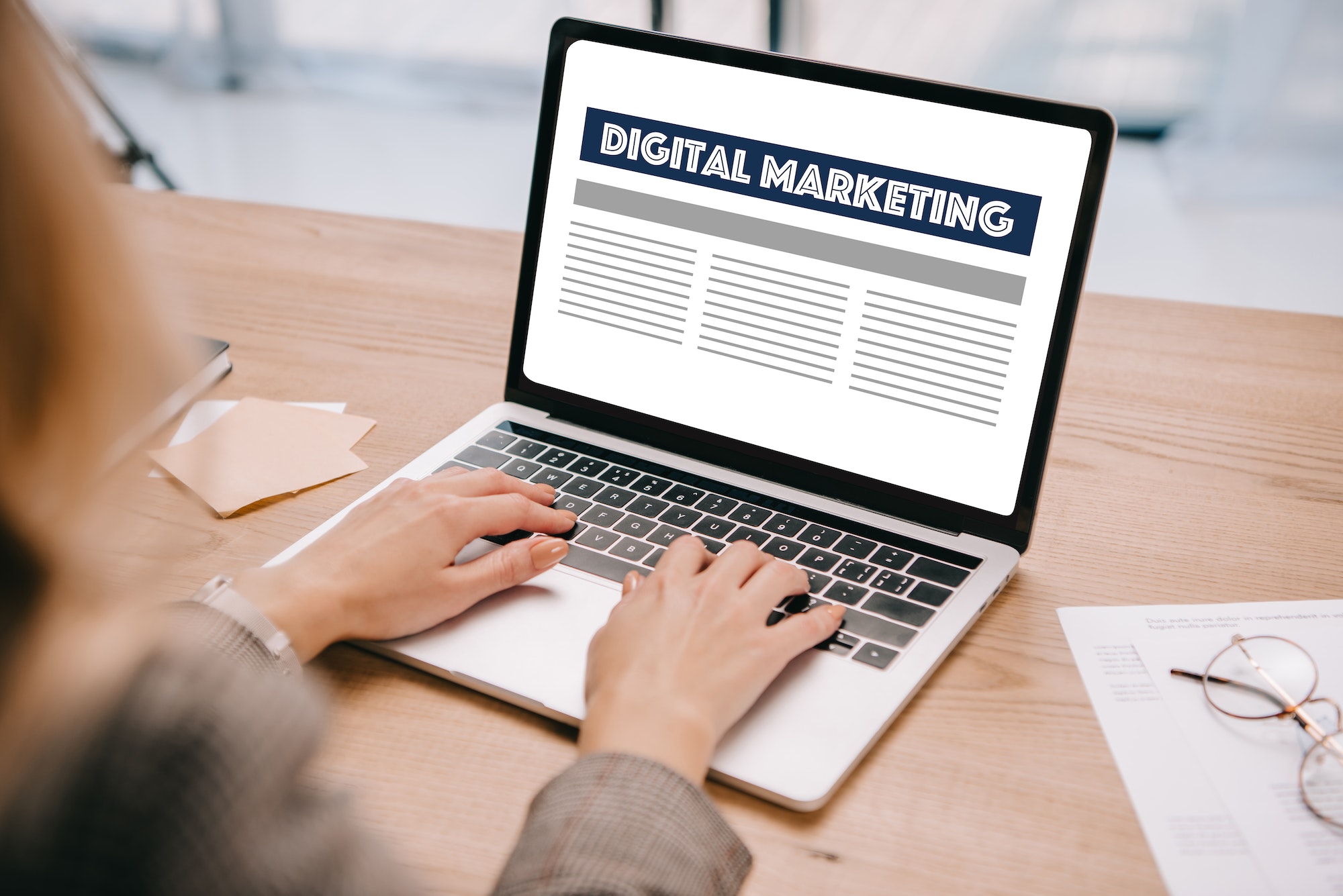 partial view of businesswoman typing on laptop with digital marketing at workplace